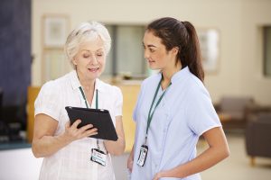 Female Consultant In Meeting With Nurse Using Digital Tablet